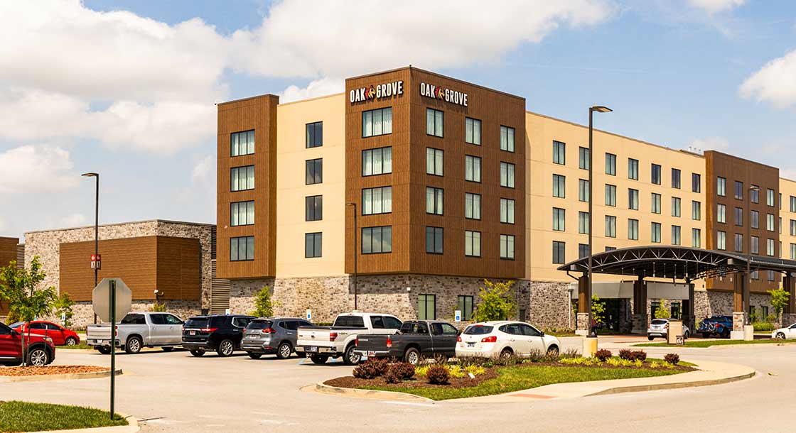 The outside of Oak Grove Hotel with some cars parked in front of it.