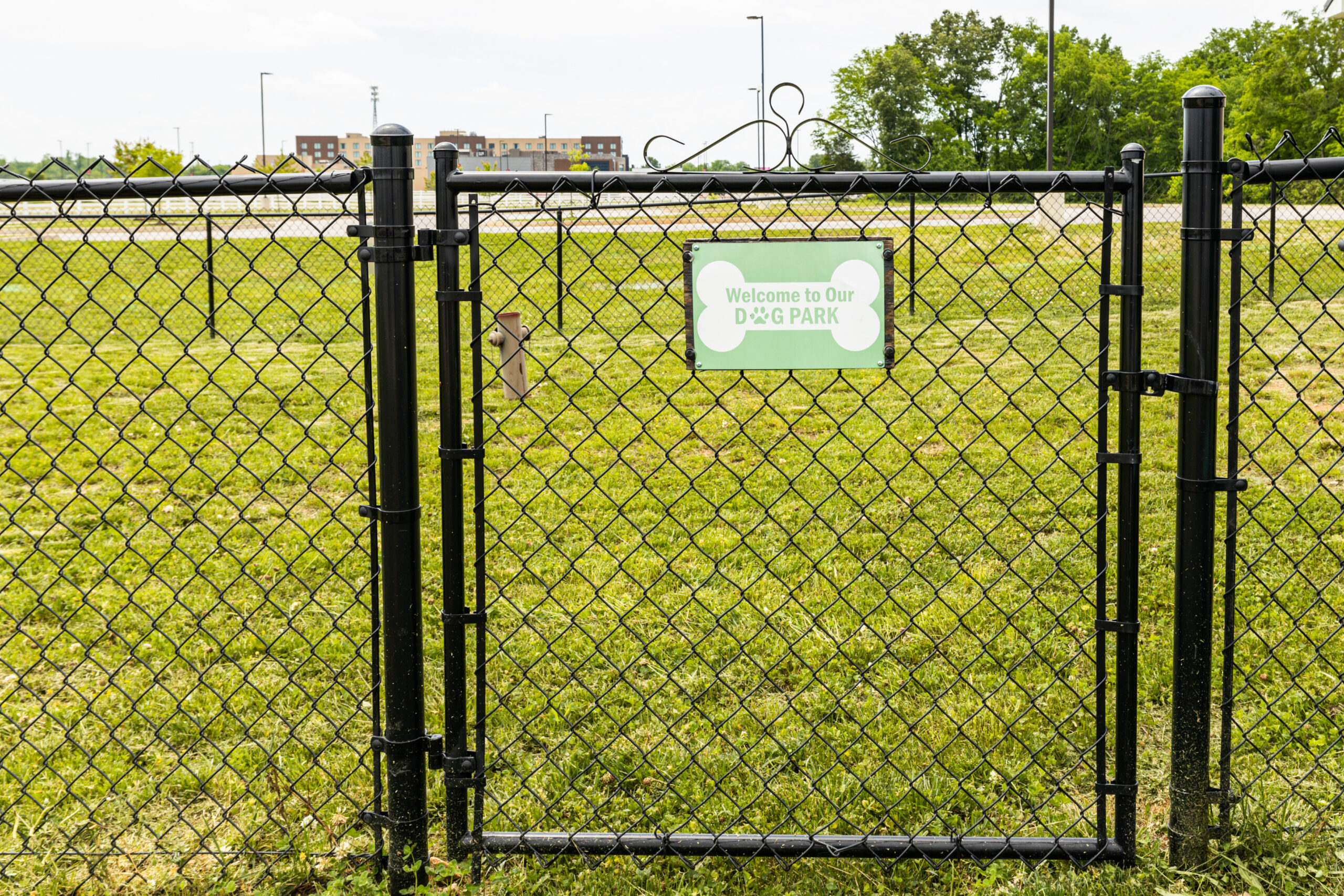 "Welcome to our Dog Park" sign on a fence.