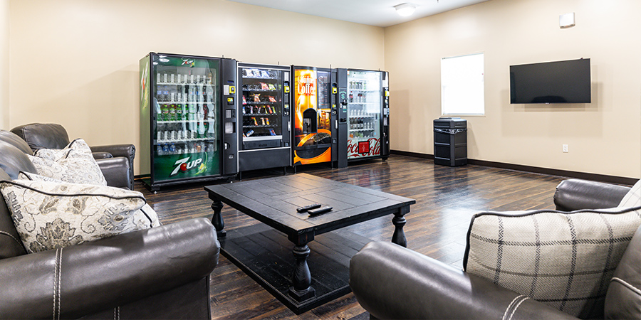 Couches and a table facing a TV, with vending machines in the background